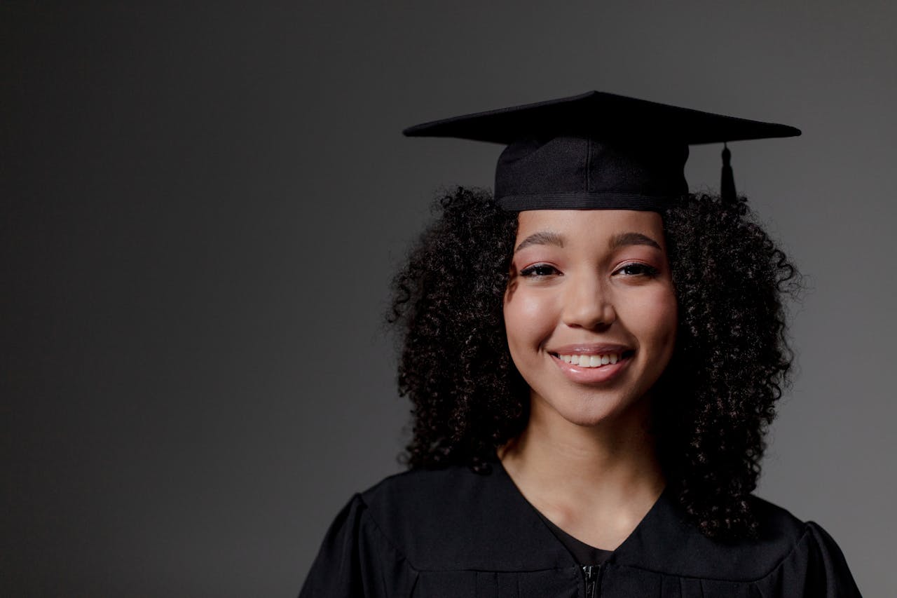 The Art of Drawing Readers In: Your attractive post title goes here Portrait of a smiling graduate wearing a cap and gown, capturing a proud and joyful moment indoors.